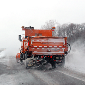 photo of snowplow putting down deicing mixture